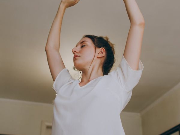Person stretching peacefully in a bright, sunlit room.